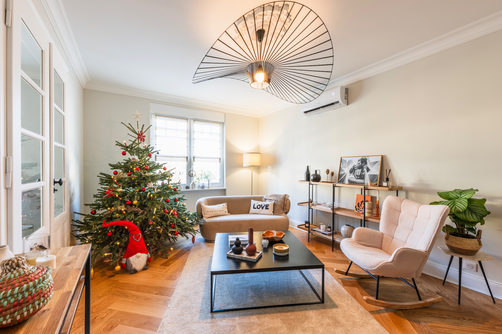 Photographie d'Architecture - Salon Moderne avec Lustre Design Salon spacieux avec parquet en bois clair, sapin de Noël décoré et grand lustre design noir suspendu.