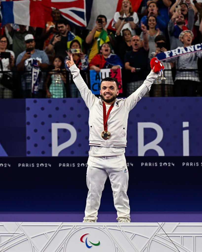 Charles Noakes, athlète français de para-badminton, célèbre sa médaille d'or sur le podium Paris 2024.