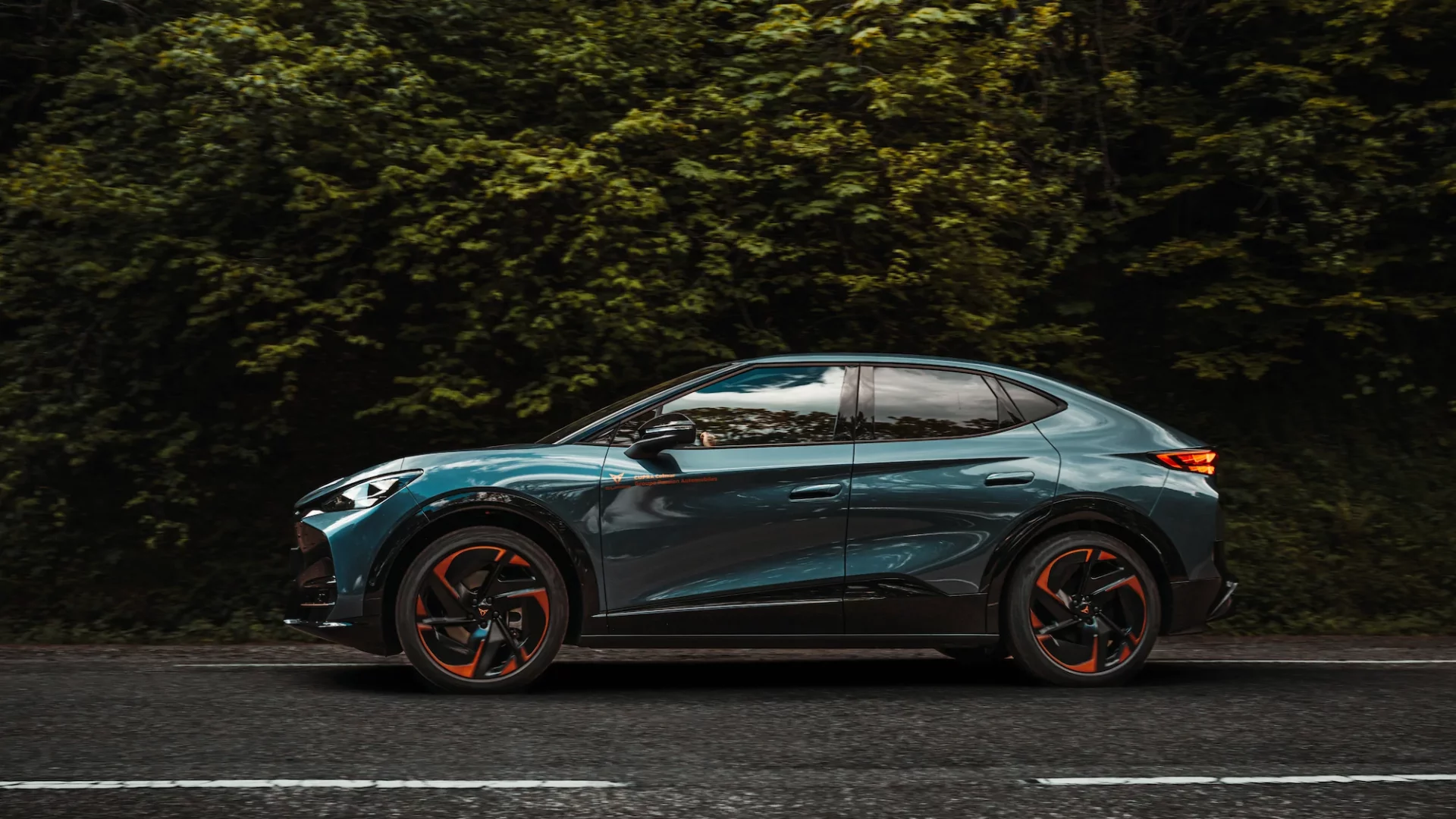 cupra-tavascan-coupe-suv-panning-route-alsace Cupra Tavascan électrique bleu en mouvement, effet de panning sur la Route des Vins d'Alsace.