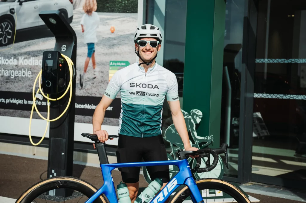 Portrait d'un cycliste en maillot Škoda We Love Cycling devant la concession de Colmar.