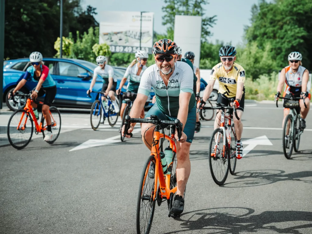 Groupe de cyclistes souriants participant aux Boucles Skoda à Colmar lors d'un événement sportif.