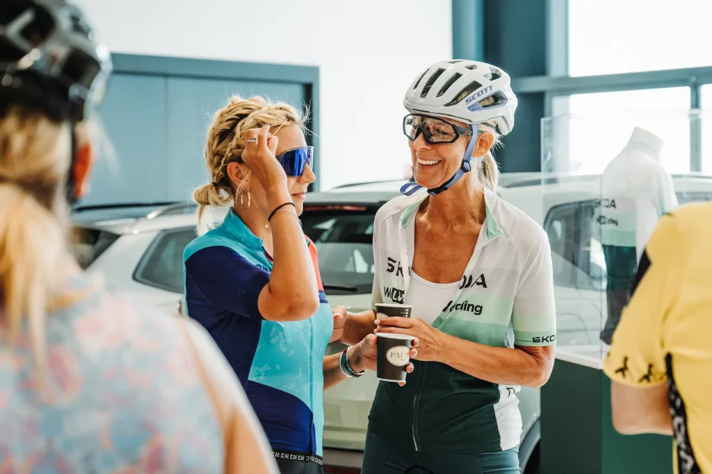 Deux cyclistes discutent avec un café lors de l'accueil des Boucles Škoda à Colmar.