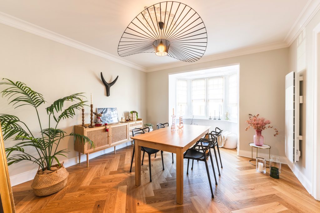 Photo immobilière de salle à manger scandinave moderne avec parquet chevrons et lustre design.