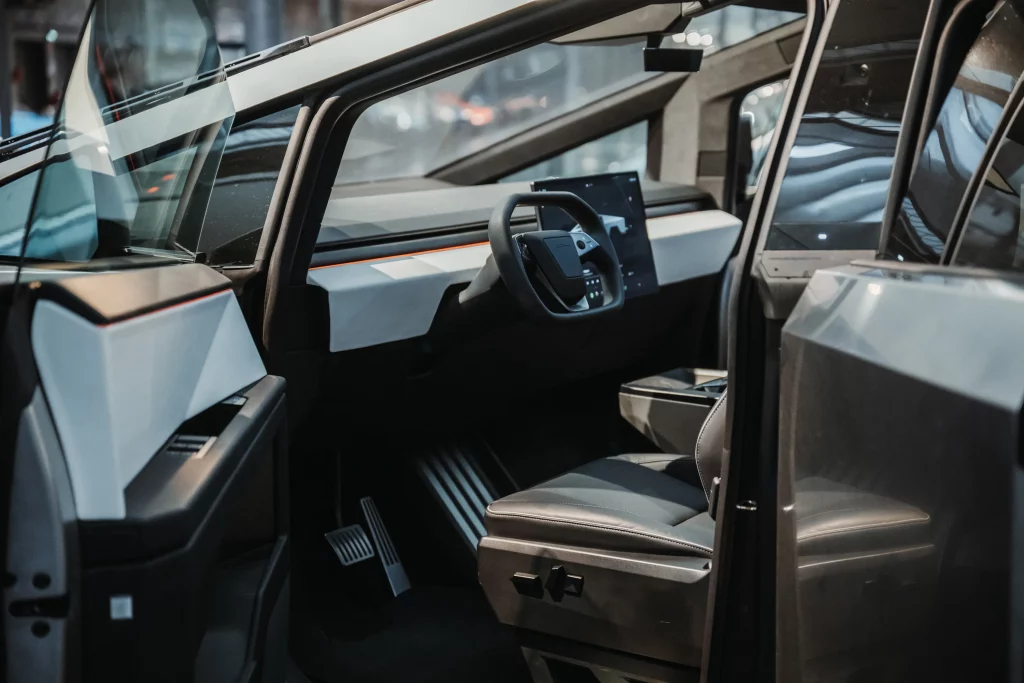 Intérieur du Tesla Cybertruck : tableau de bord minimaliste, volant yoke et siège conducteur en cuir.