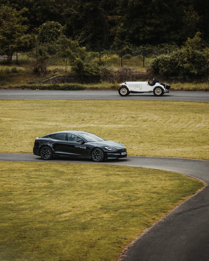 Contraste puissant entre une Tesla Model S noire et une voiture ancienne classique sur l'autodrome de Mulhouse.